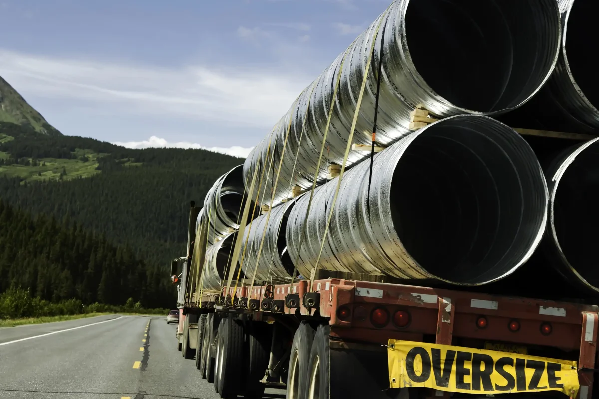 Truck carrying oversized load of pipes